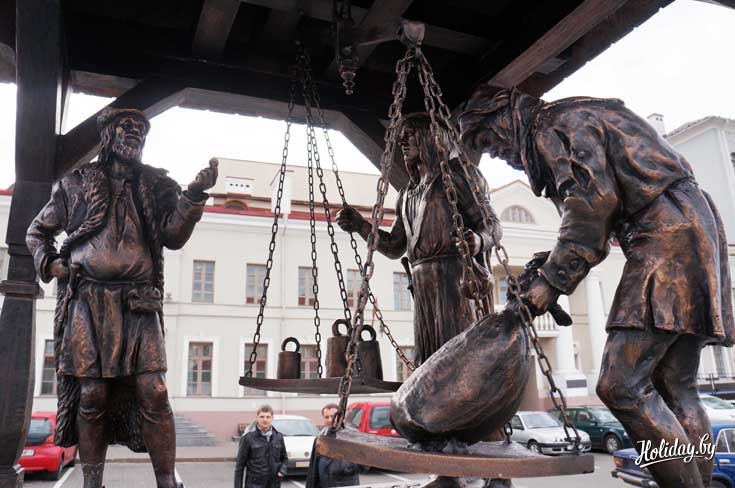 Продавец взвешивает свой товар для купца, который с ним торгуется. А рядом стоит представитель ратуши, который внимательно наблюдает за процессом